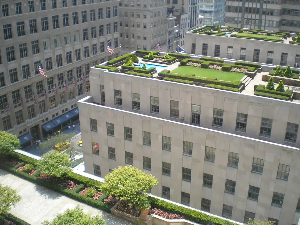 The rooftop gardens of Rockefeller Center seen from above: lawns, clipped hedges and a reflecting pool on the roofs along Fifth Avenue.