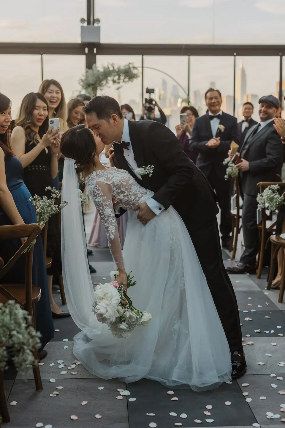 After the ceremony, the groom dips the bride for a kiss in the aisle as guests cheer and take photos.