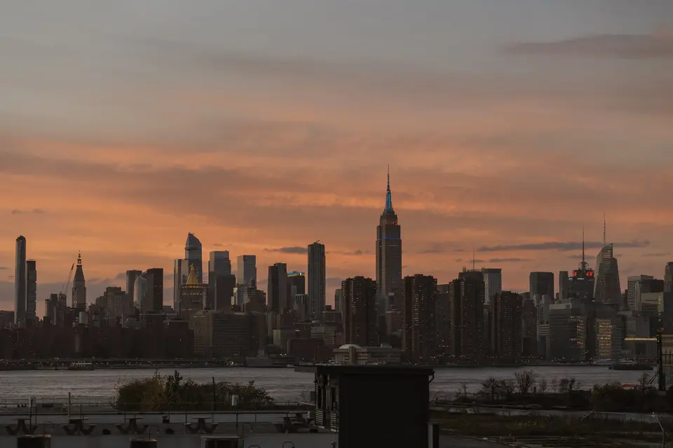 The Manhattan skyline at sunset, the Empire State Building against an orange sky.