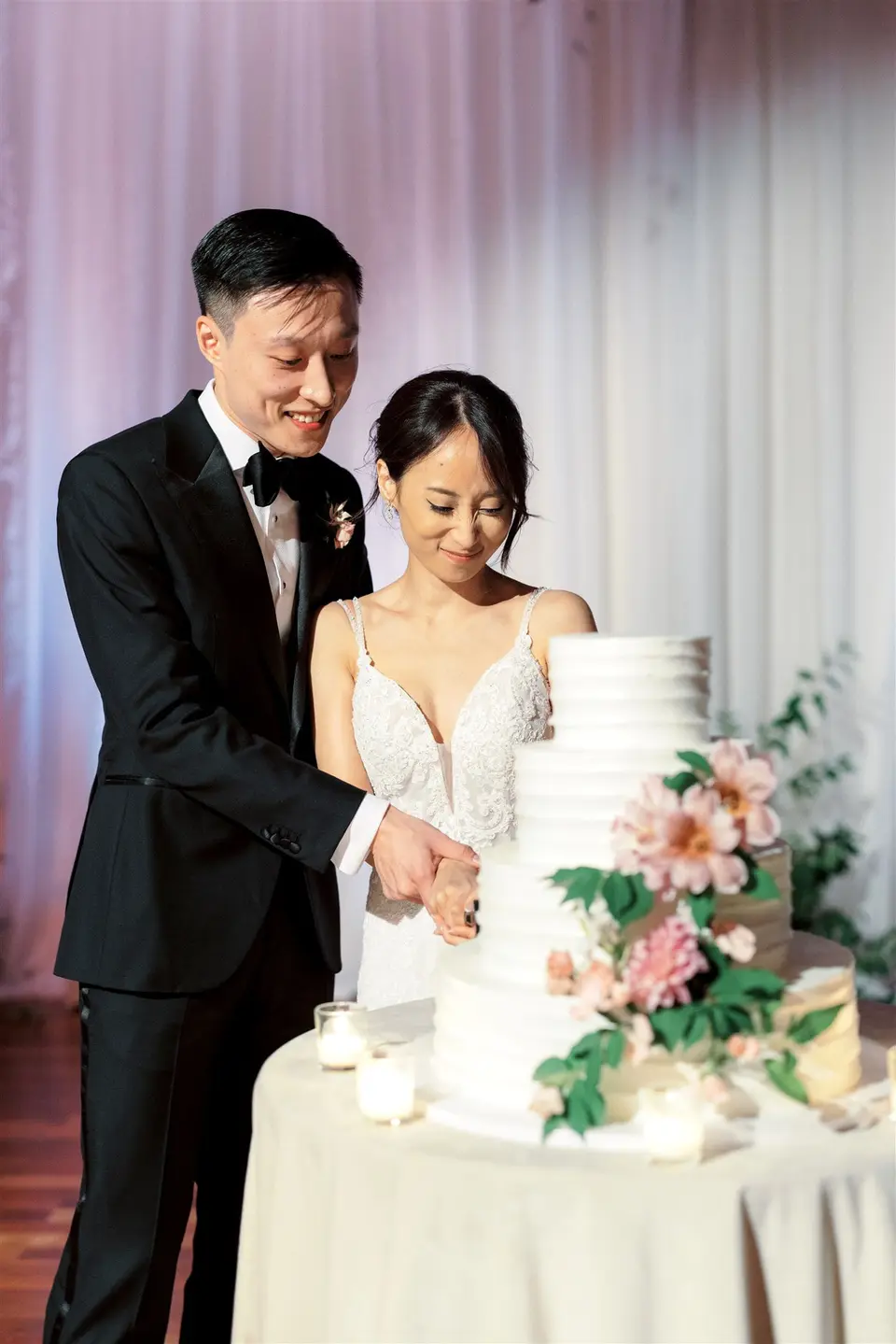 The couple cut the cake together, smiling.