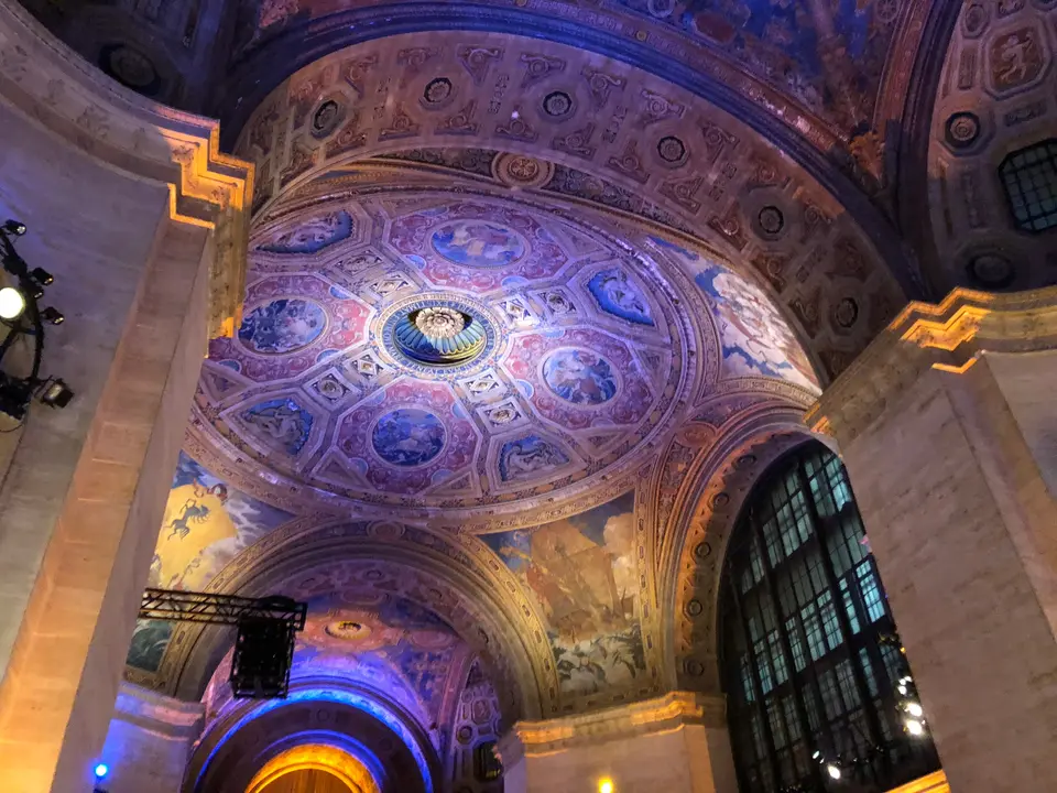 The painted and gilded dome of the Great Hall of the Cunard Building at 25 Broadway, lit in violet and gold for an evening event.