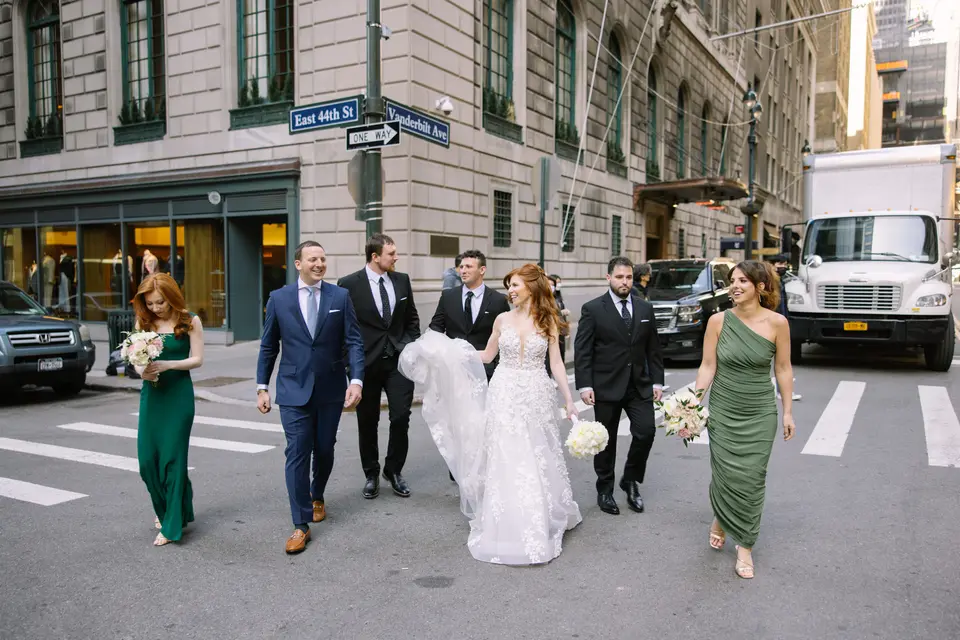 The couple and their wedding party cross East 44th Street at Vanderbilt Avenue, bridesmaids in green.