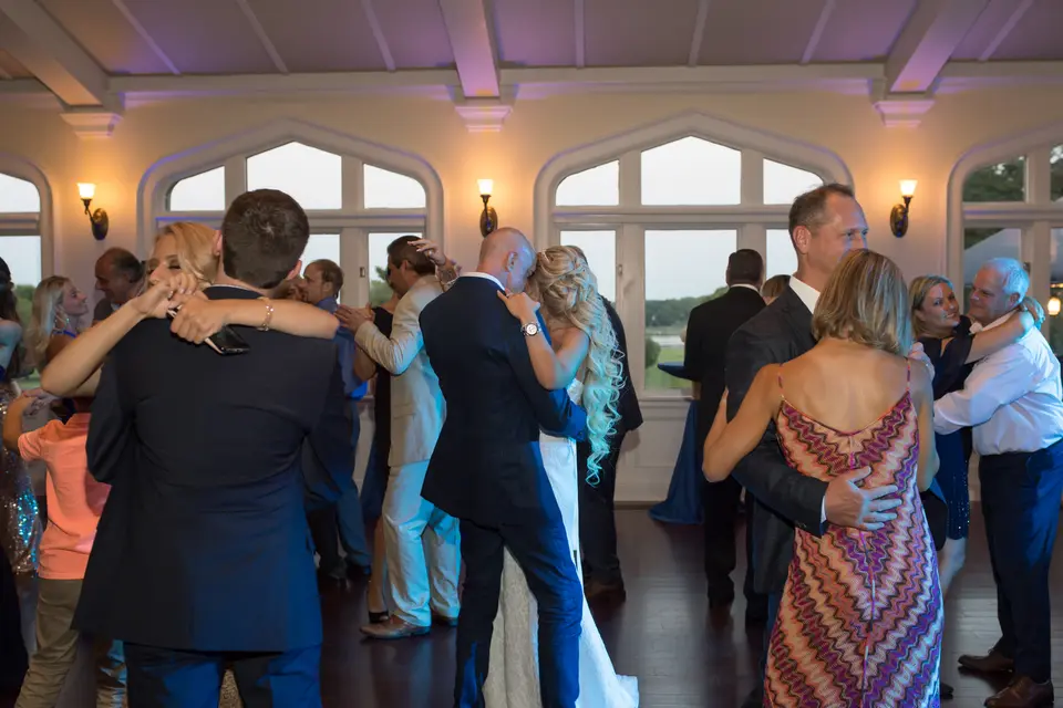 Guests dance close together in the reception room at dusk.