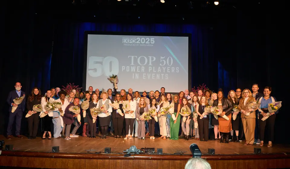 The Top 50 Power Players in Events stand together on stage at The Event Planner Expo 2025, holding bouquets, the title projected behind them.