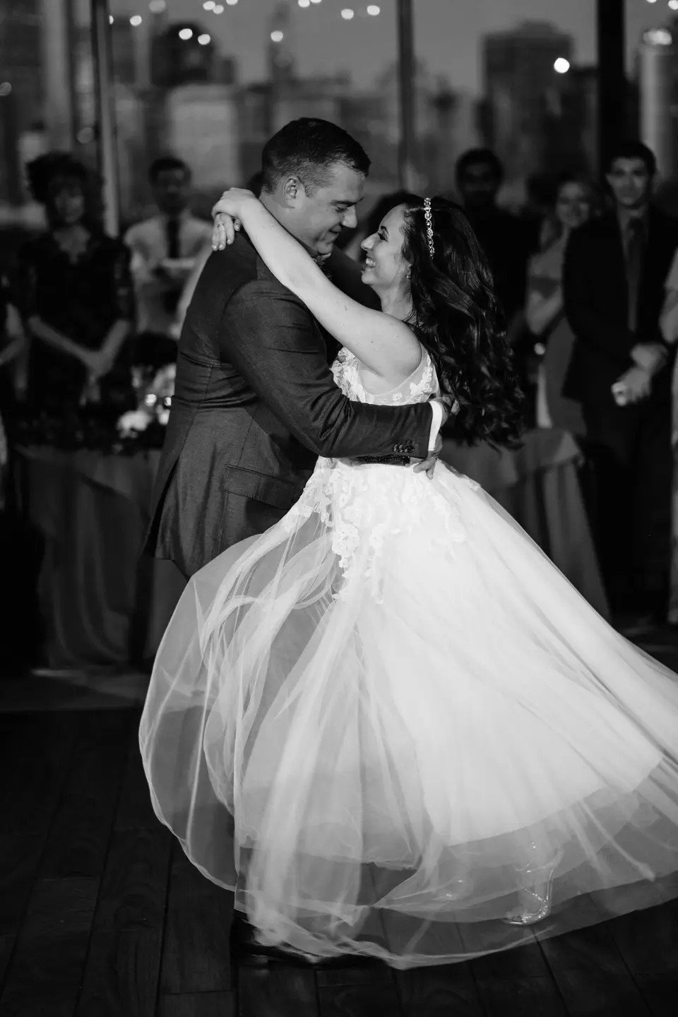 The couple turn in their first dance, the bride's skirt swinging out. Black and white.