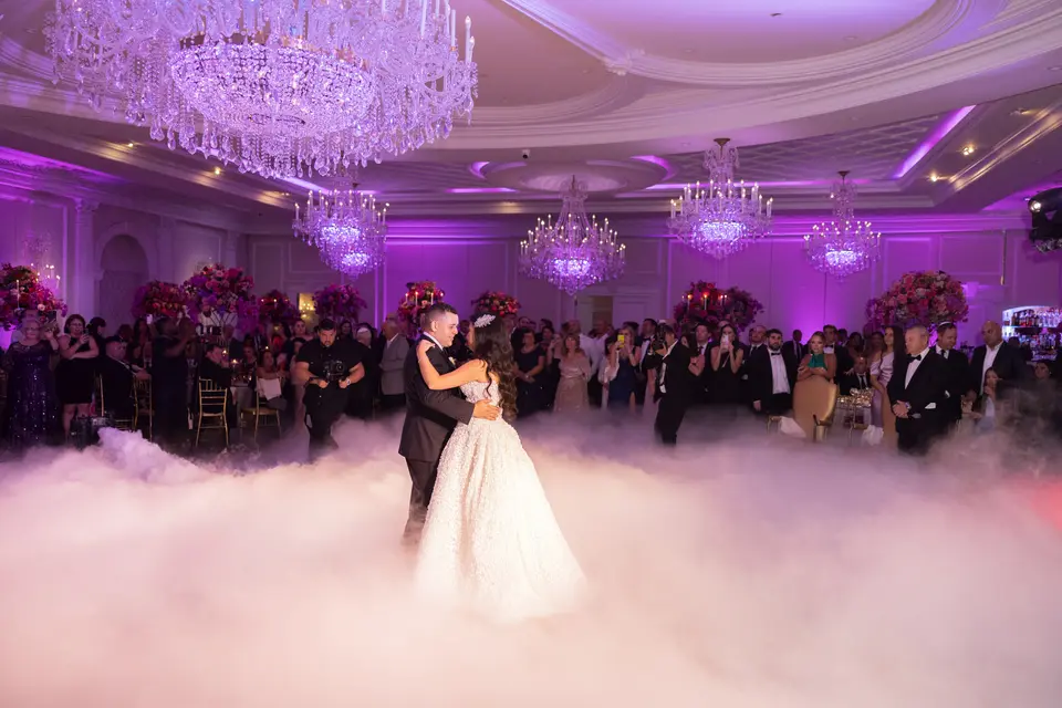 The couple dance in a low cloud that covers the floor, the ballroom glowing violet around them.