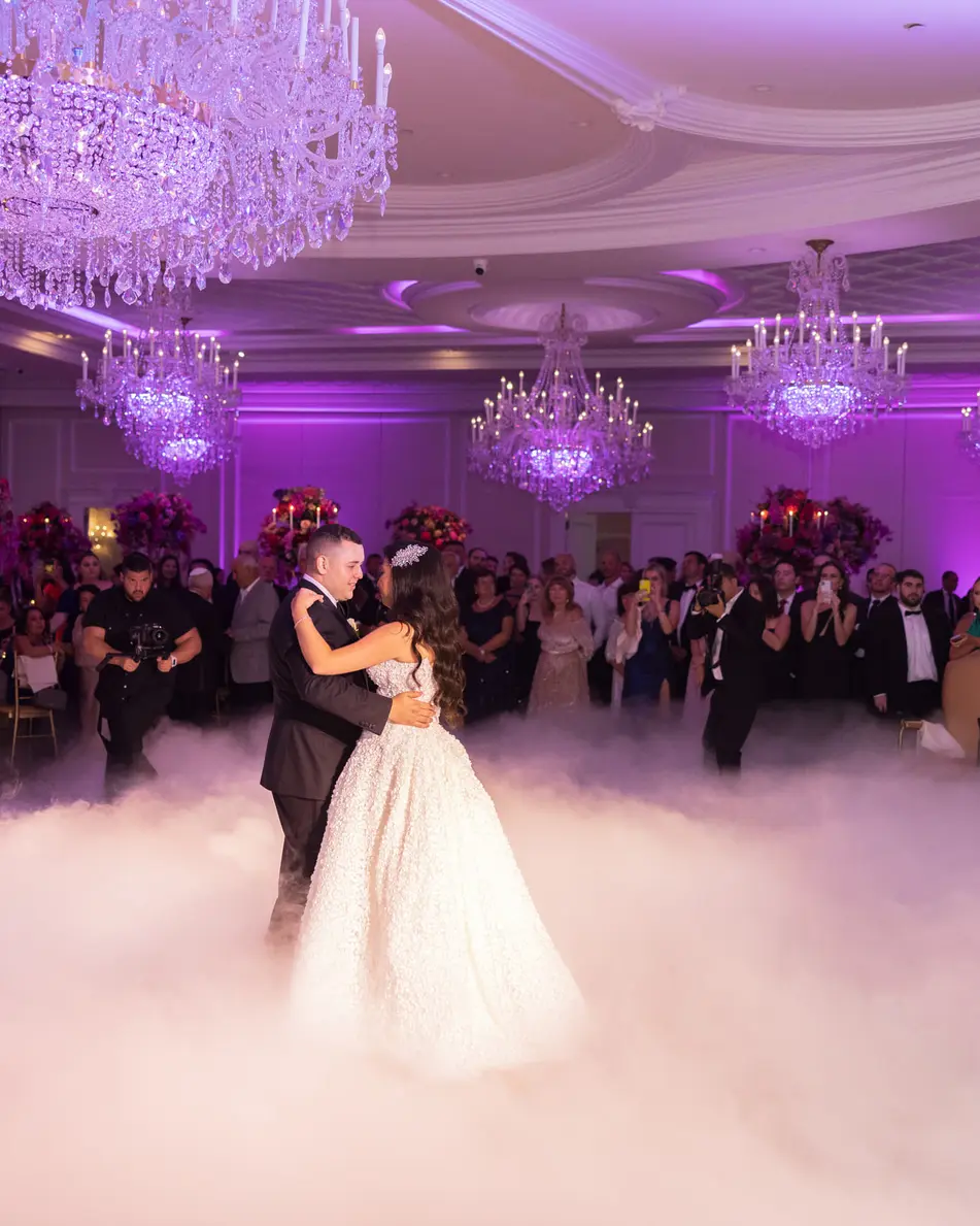 The couple dance in a low cloud that covers the floor, the ballroom glowing violet around them.