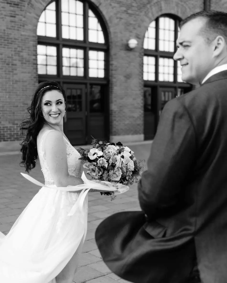 Beneath the brick arches of the terminal, the groom turns to see the bride for the first time. Black and white.