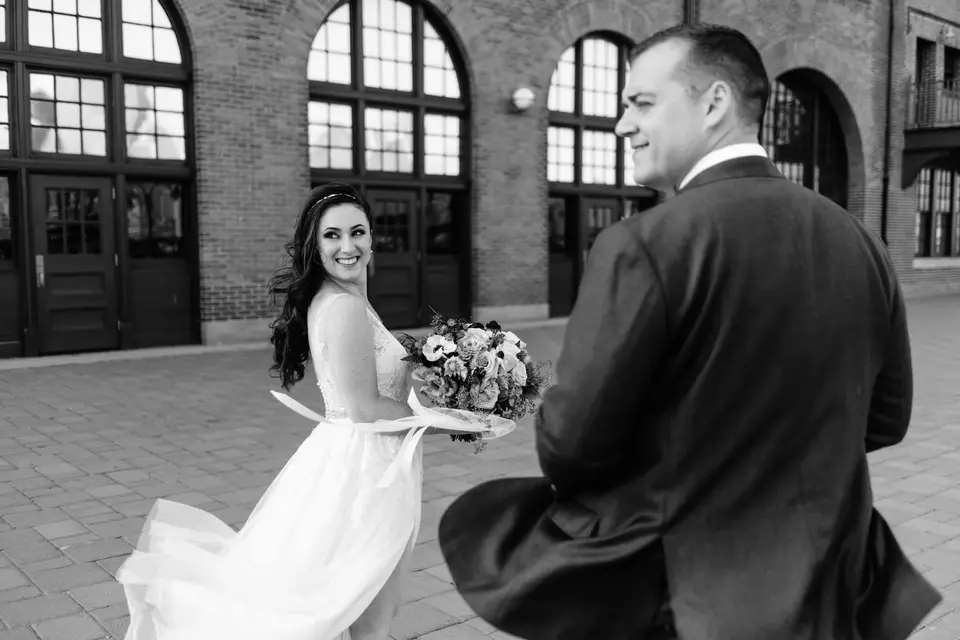 Beneath the brick arches of the terminal, the groom turns to see the bride for the first time. Black and white.