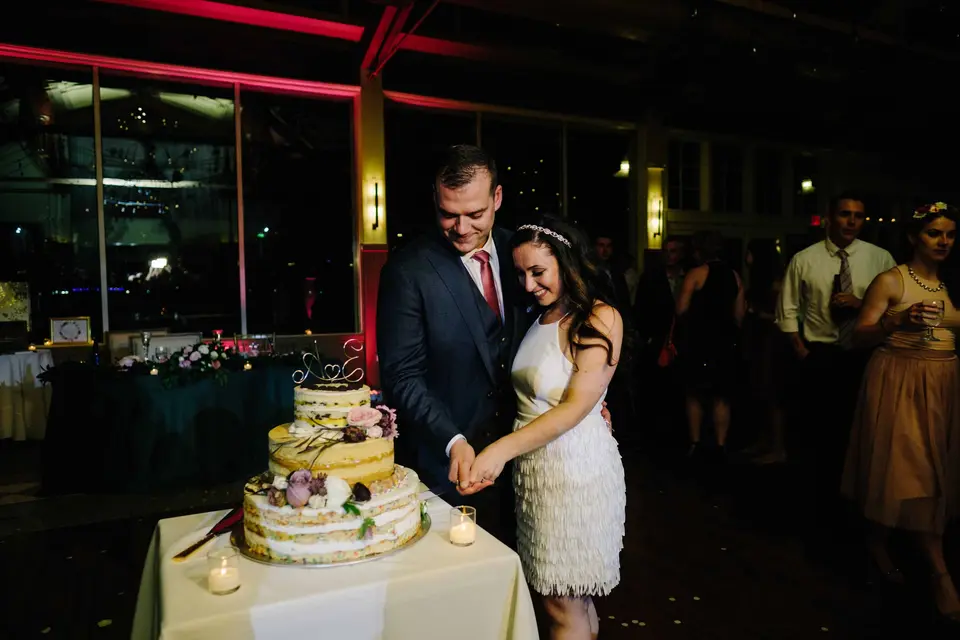 The bride, changed into a short fringed dress, cuts the naked cake with the groom.