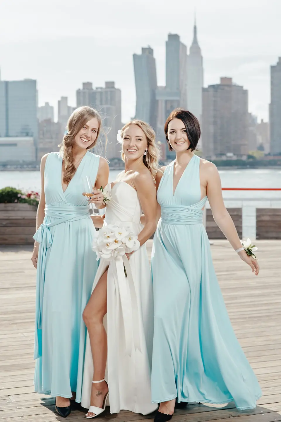 The bride between two bridesmaids in pale blue gowns, the Empire State Building rising behind them.