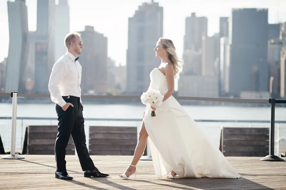 The bride and groom walk toward each other along the waterfront, Midtown towers across the river.