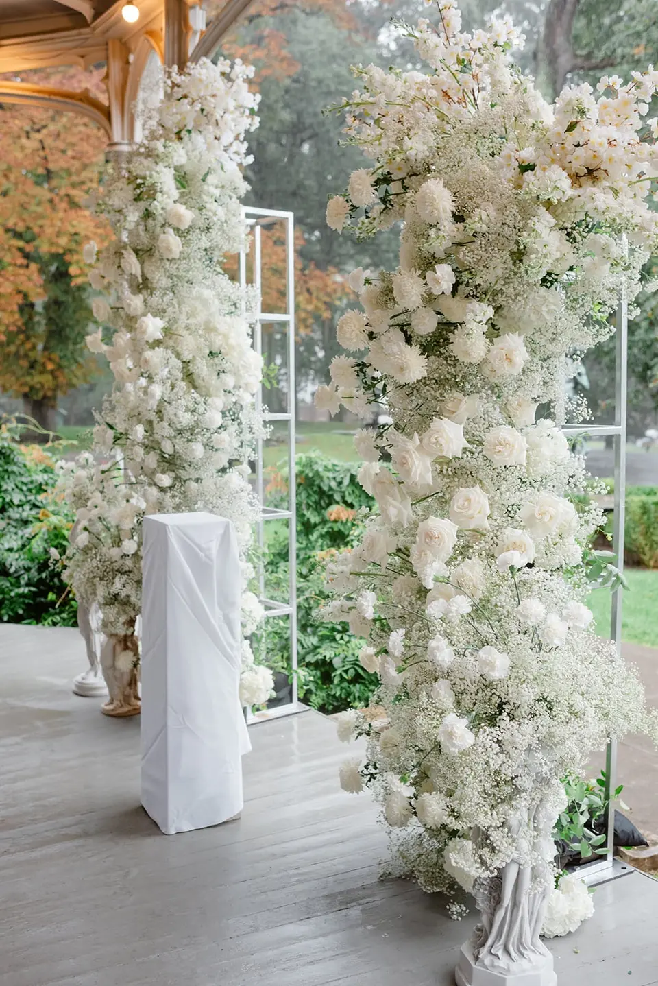 Tall columns of white flowers and baby's breath framing the ceremony on the veranda.