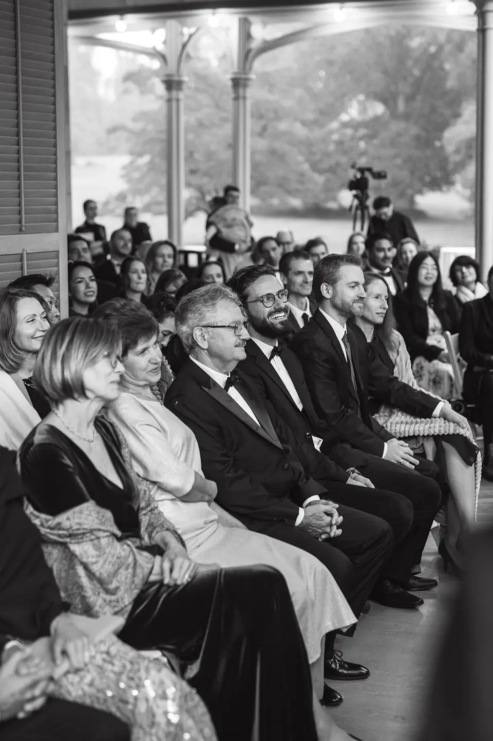 Guests seated on the veranda, watching the ceremony. Black and white.
