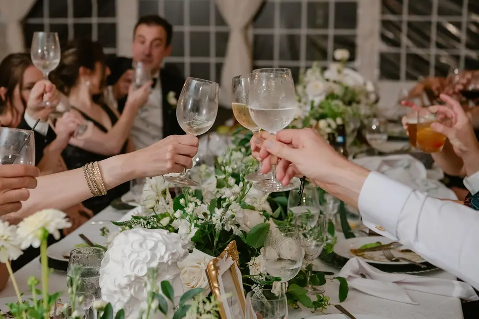 Guests raise their glasses in a toast across the flowered table.