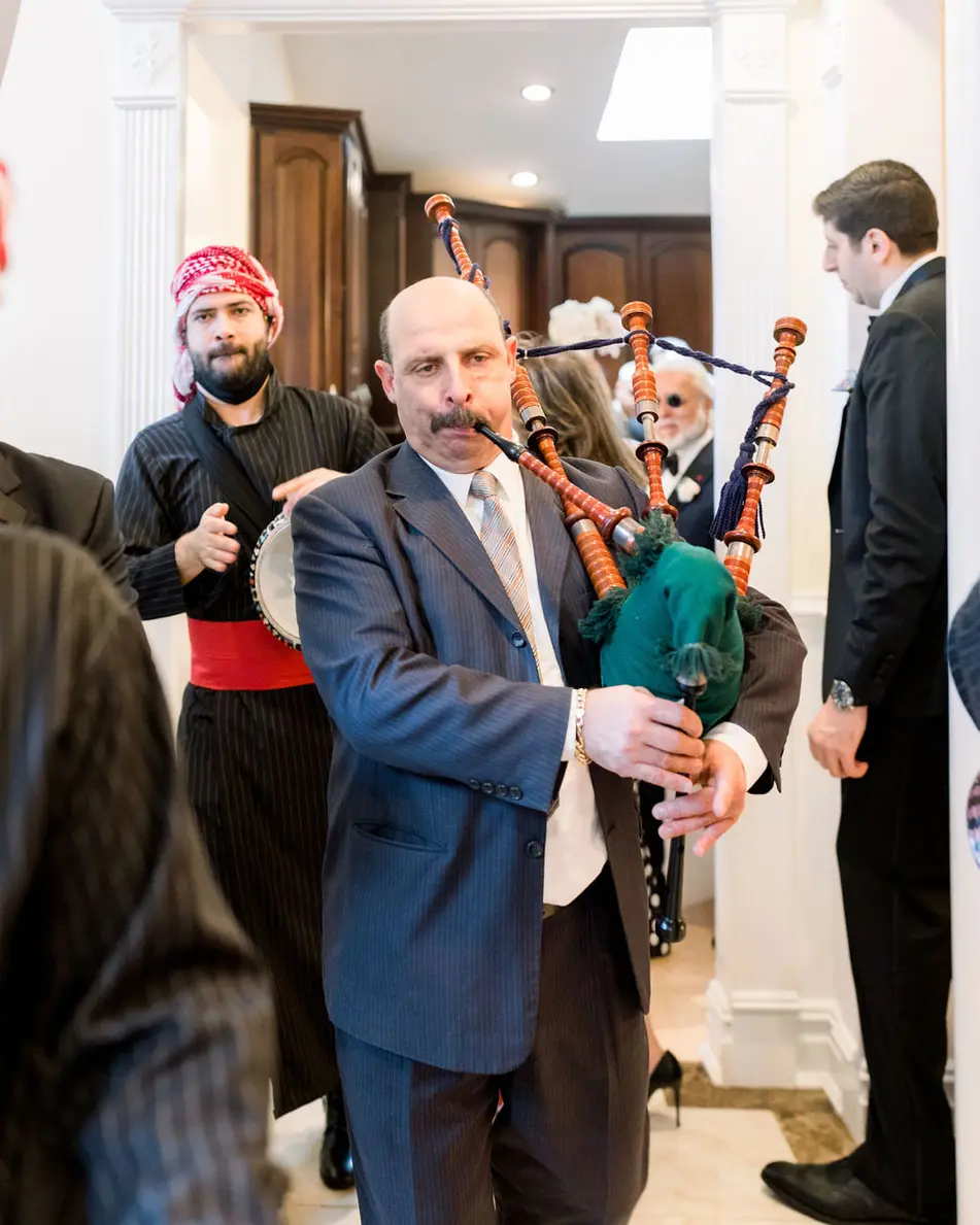 At the family home, a musician plays bagpipes and another a drum as the groom arrives through the door.