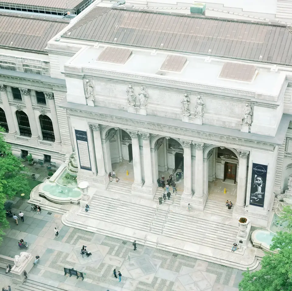 The New York Public Library on Fifth Avenue seen from above, its steps and fountains in soft daylight.