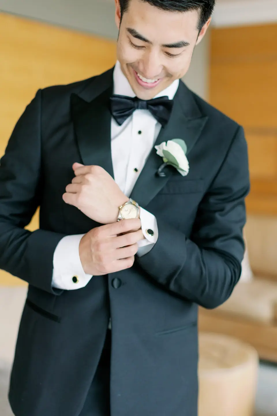 The groom smiles as he fastens his cufflink.