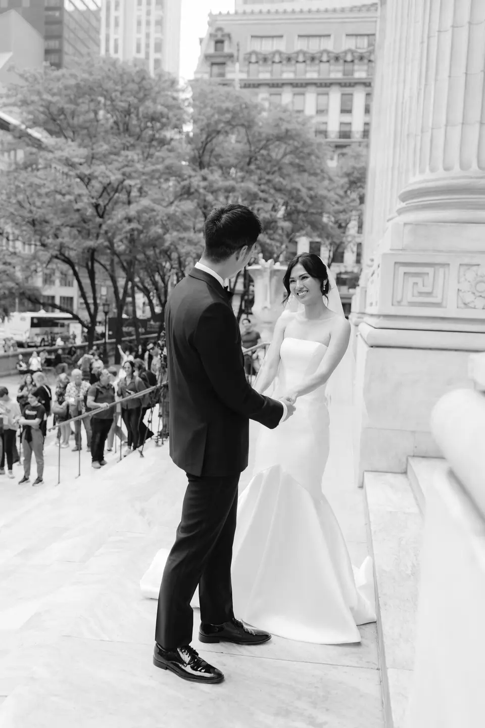 The bride and groom on the library steps, a crowd along Fifth Avenue below. Black and white.