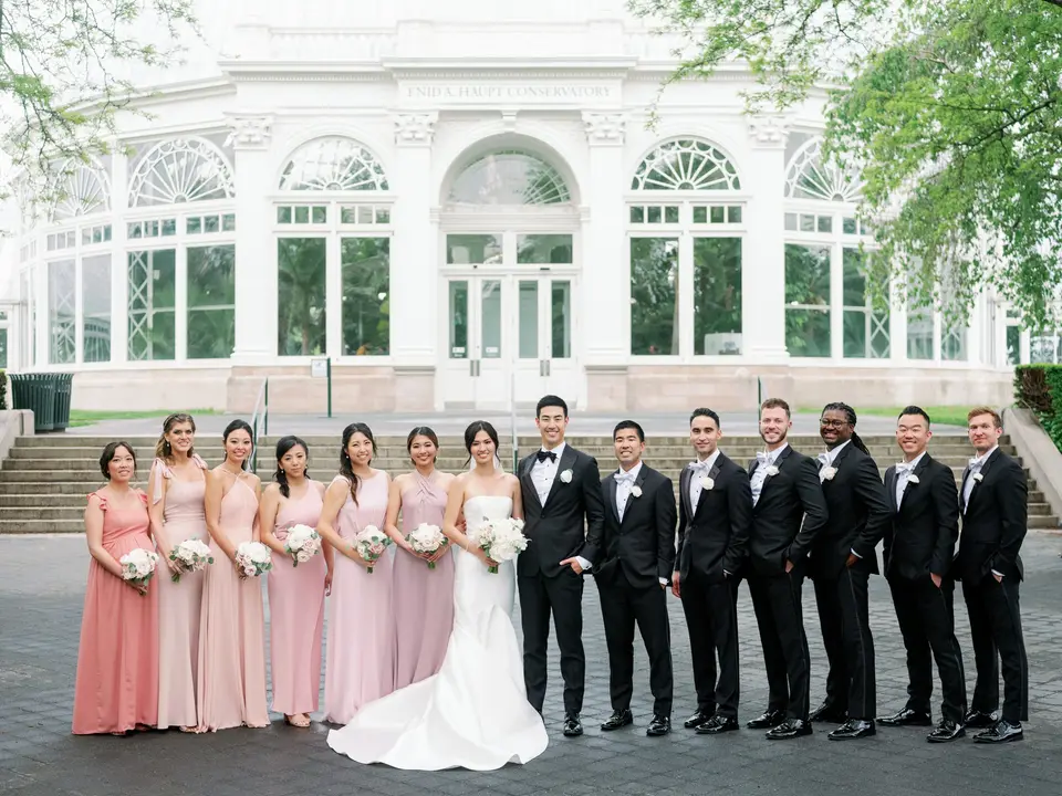 The wedding party in front of the conservatory, the bridesmaids in shades of pink.