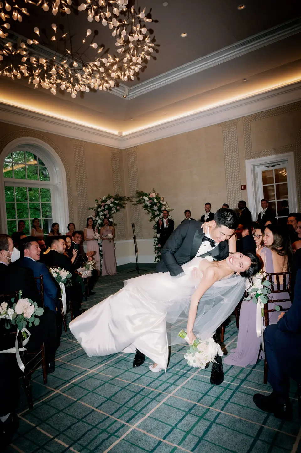 After the ceremony, the groom dips the bride for a kiss in the aisle as guests watch.