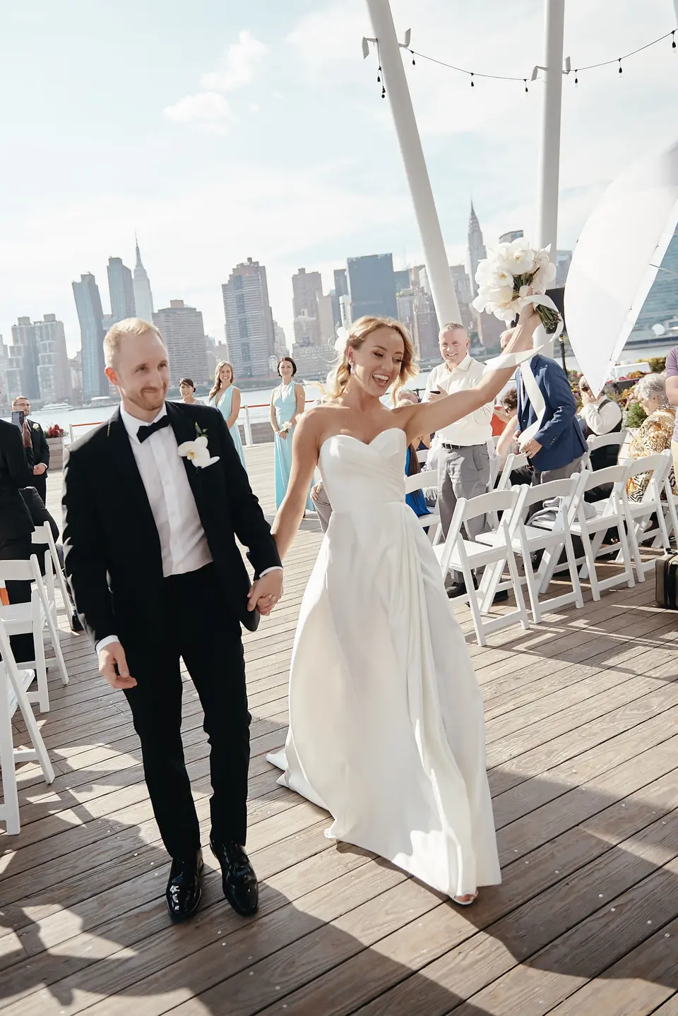 Married, the couple walk up the aisle on the deck as guests applaud.