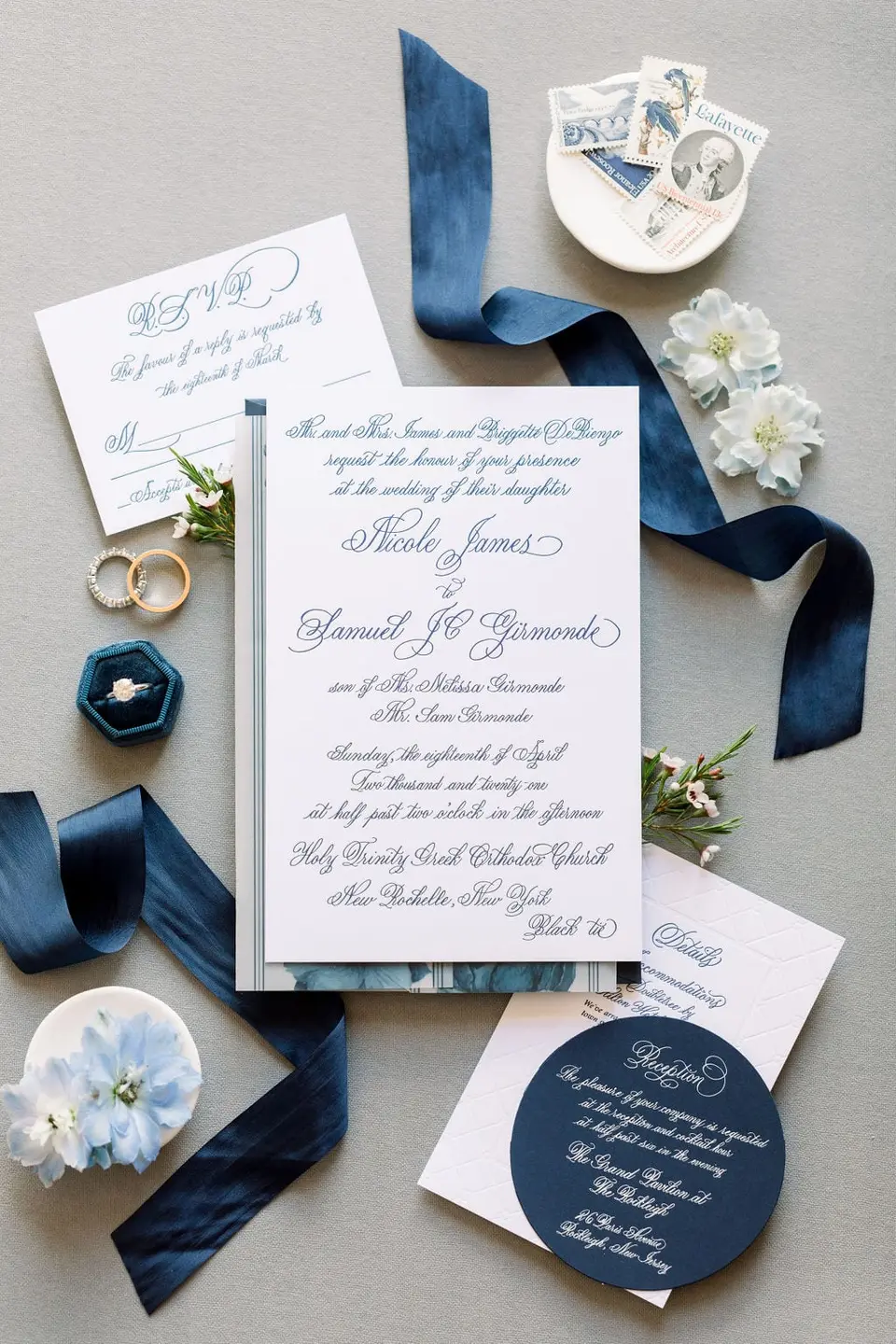 The invitation suite in navy and white with blue ribbon, rings, pale blue flowers and a velvet ring box.