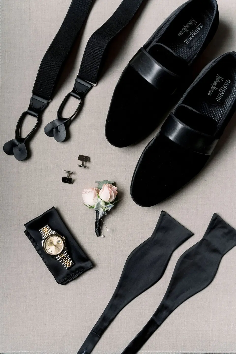 The groom's black velvet loafers, suspenders, bow tie, watch, cufflinks and a blush boutonniere.
