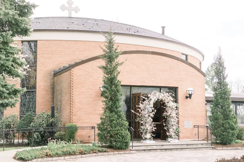 The church entrance framed by an arch of white and blush flowers.