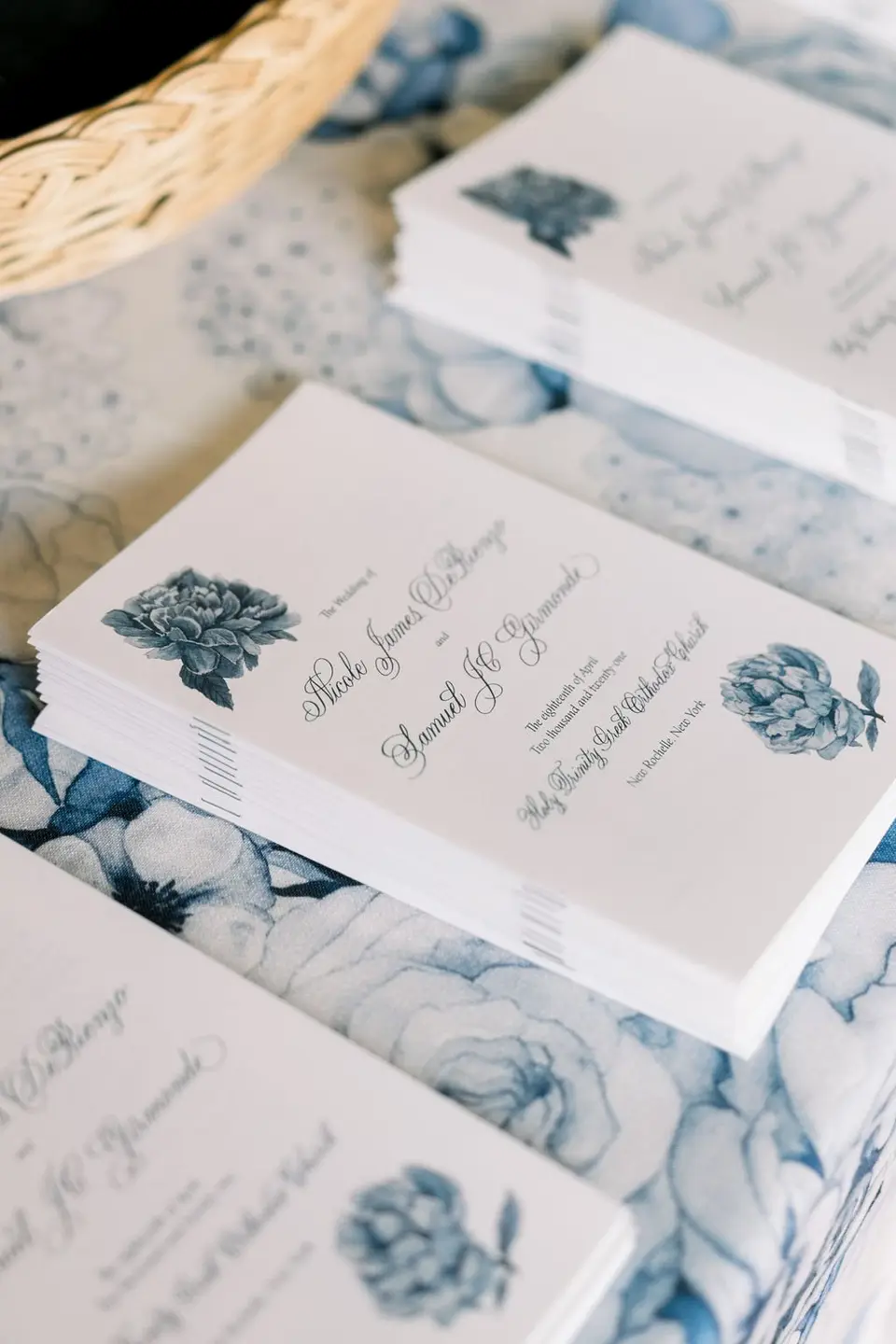 Ceremony programs printed with blue flowers, stacked on blue floral paper.