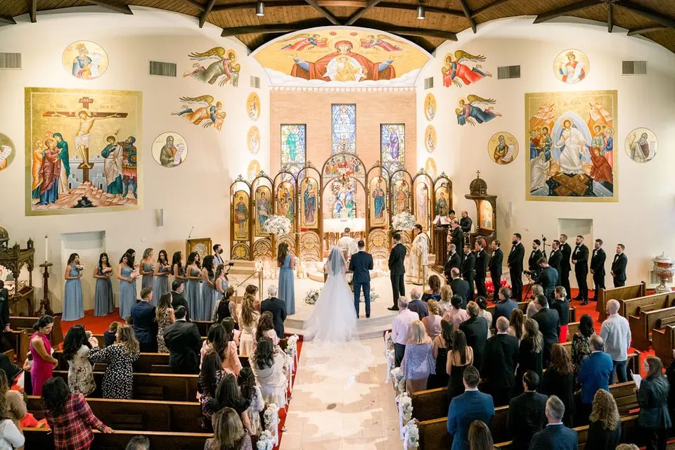 The ceremony seen from the back of the church, the wedding party at the altar beneath walls of icons.