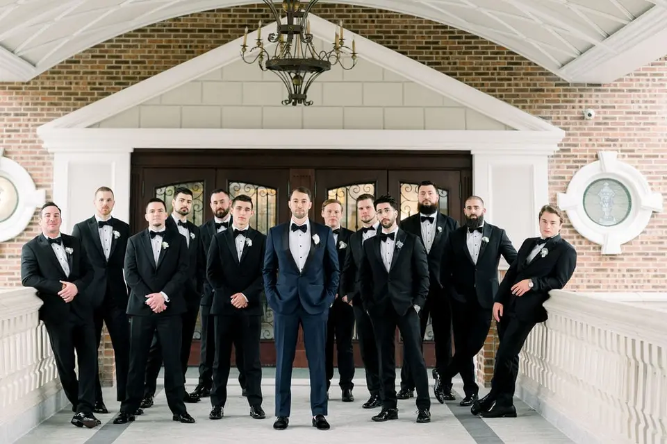 The groom and his groomsmen on a balcony before the entrance doors.