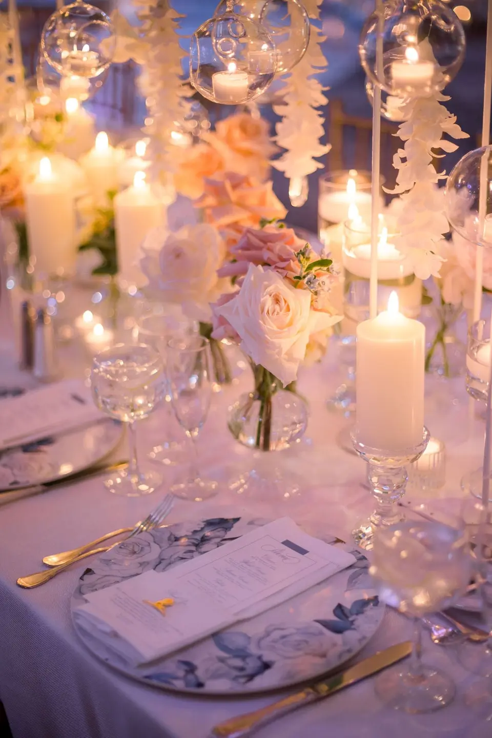Pillar candles and pink roses above a menu on a blue floral charger.