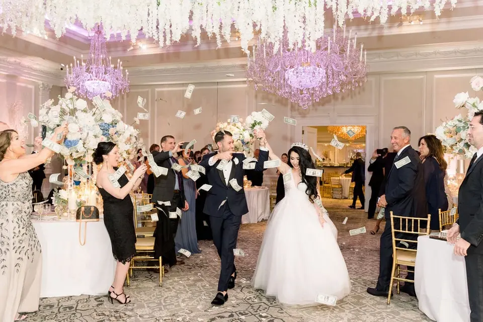 Guests shower the bride and groom with money as they dance into the ballroom.