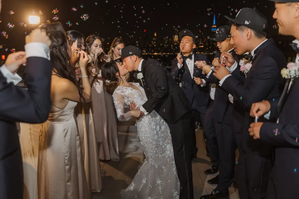 At night, the couple kiss as the wedding party blow bubbles around them.