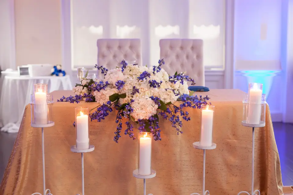 The couple's table in gold linen with white and blue flowers and pillar candles.