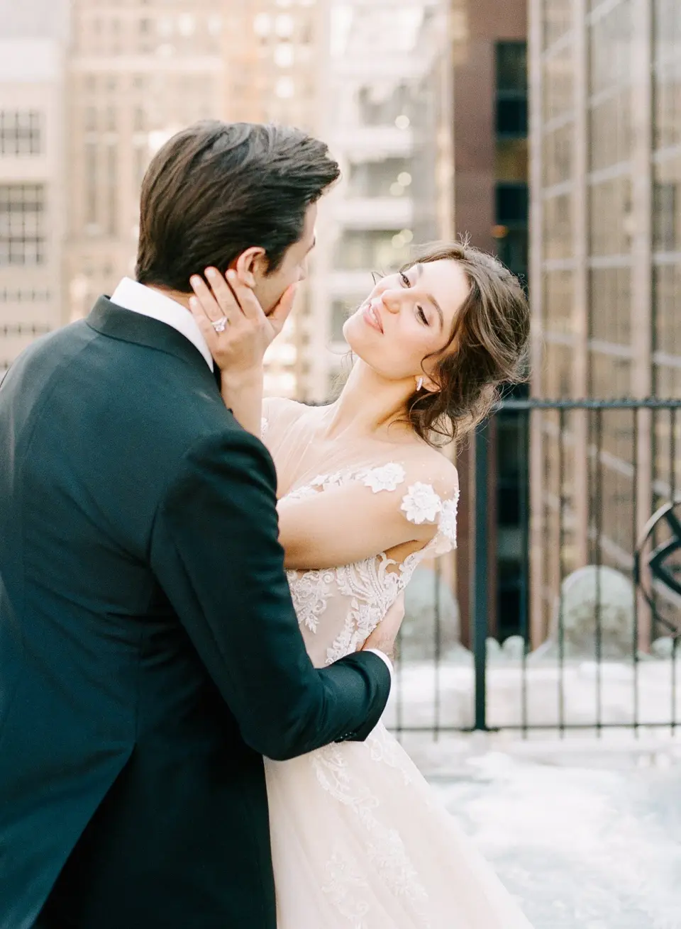 The groom cups the bride’s face as she laughs, the towers of Midtown behind them.