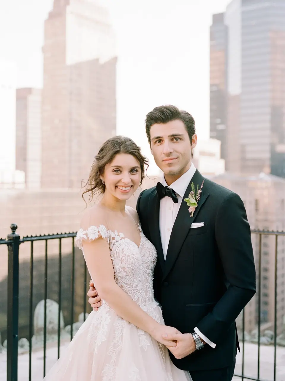 The bride and groom stand close together at the terrace railing.