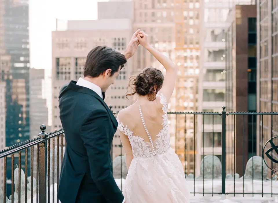 The groom twirls the bride on the terrace, the buttons of her gown down her back.