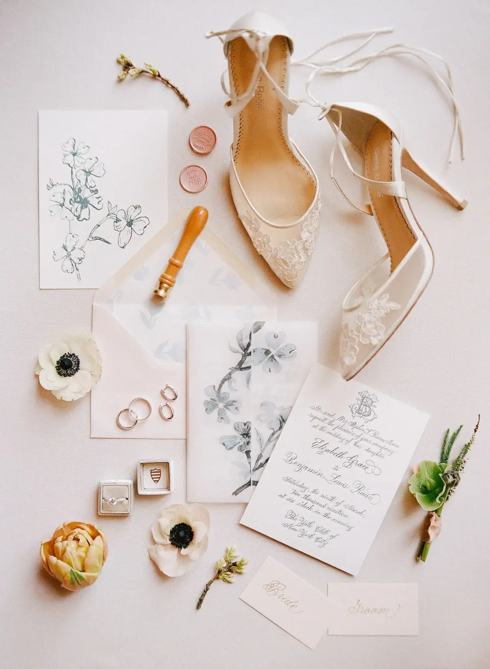 Lace heels, the rings, the invitation, a wax seal and anemones laid out together.