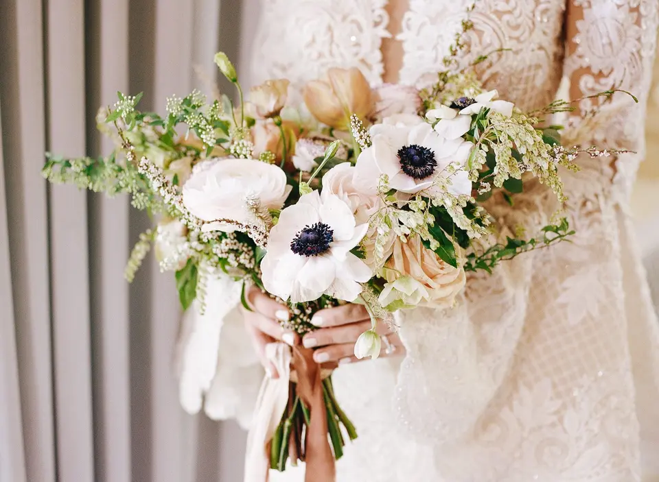 Close on the bouquet of white anemones and blush flowers in the bride’s hands.