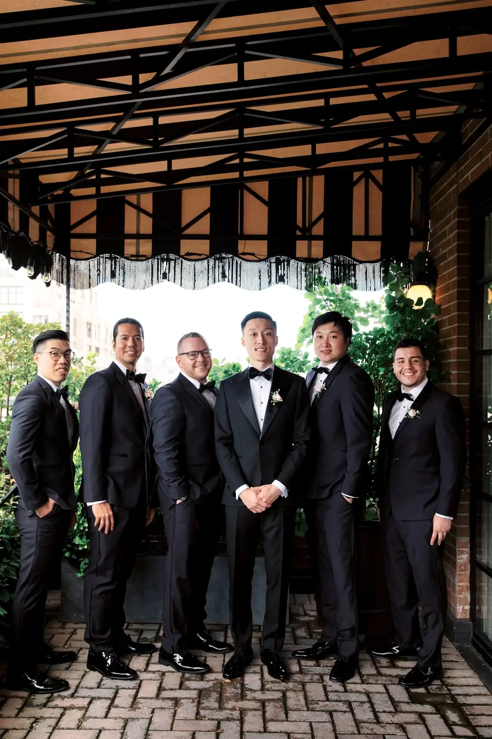 The groom and his groomsmen beneath a striped awning on the terrace.