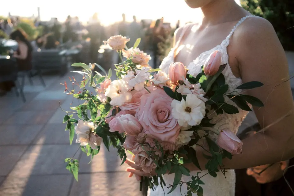 The bride's bouquet of pink roses, tulips and white flowers, lit by the low sun.