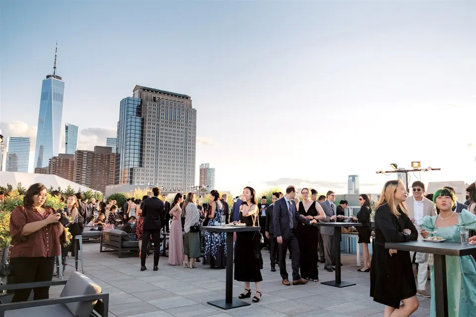 Guests at cocktail hour on the roof terrace, One World Trade Center rising behind them.