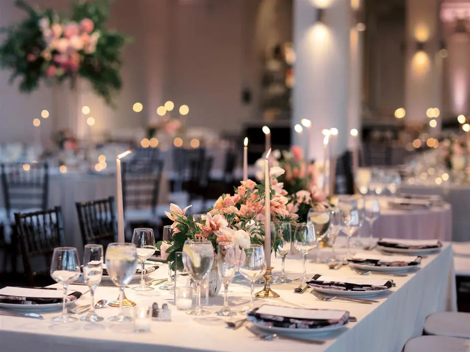 Long tables with taper candles and low pink arrangements in the dining room.