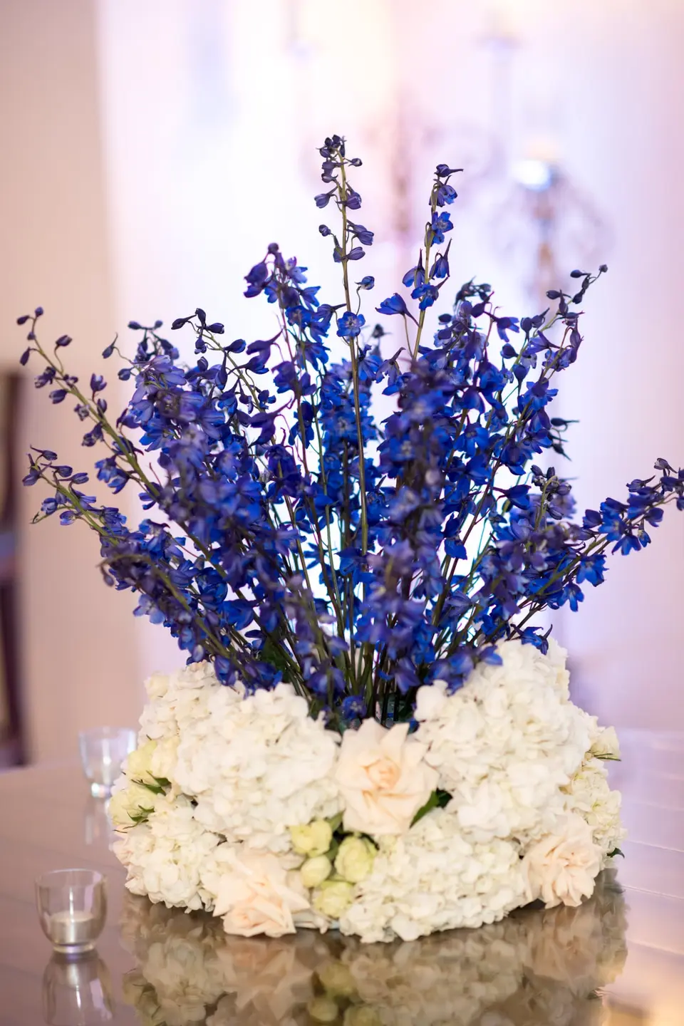 A centerpiece of blue delphinium rising from a ring of white hydrangeas.