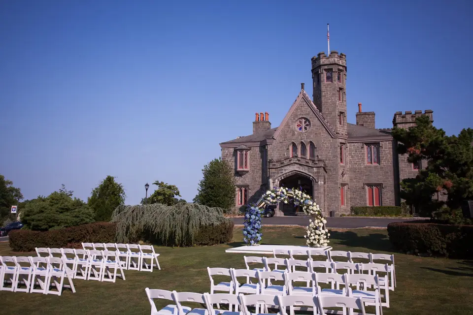 The ceremony chairs set on the lawn before the flower arch and the stone castle.