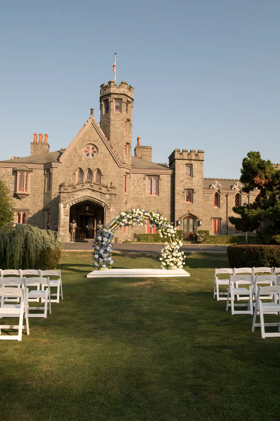 The aisle across the lawn to the arch of flowers, the castle tower behind.