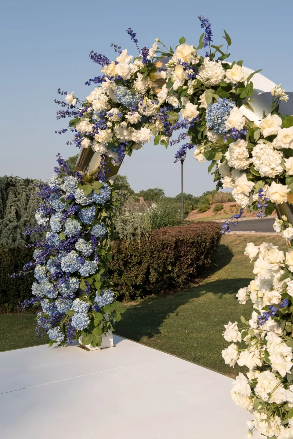 Close on the arch of white flowers, blue hydrangeas and delphinium.