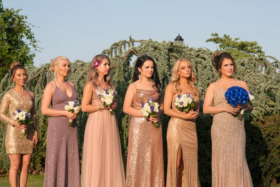 The bridesmaids in gold and blush sequins stand in a row during the ceremony.